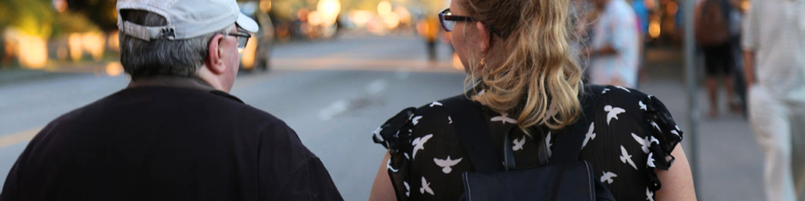 A community member walking beside a VocalEye volunteer sighted guide down the street.